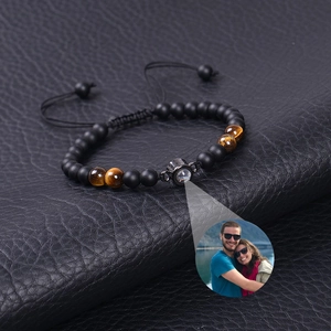 Detailed view of matte onyx and tiger eye stone bracelet with photo projection charm