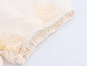 Detailansicht der elastischen Manschetten an aprikosenfarbenen Chiffonkleid mit Stickerei