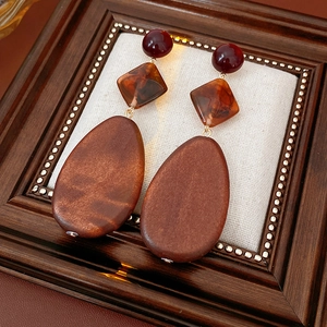 Detail of vintage drop earrings with red beads, amber resin, and wood water drop pendants