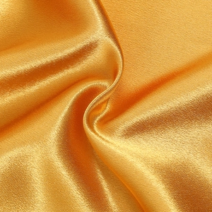 Détail du tissu satiné doré brillant avec un drapé élégant et une texture de soie lisse