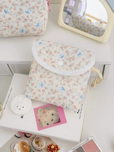 Mini sac bandoulière matelassé à fleurs avec bouton pression posé sur un livre