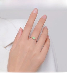 Detail of a thin S925 silver ring featuring a round green opal on a model's hand