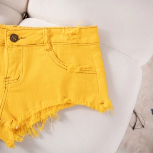 Dettaglio ravvicinato di pantaloncini di denim giallo acceso con bordi sfrangiati e grezzi