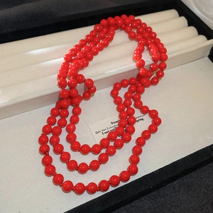 Close-up of a multilayered long red pearl necklace on a beige jewelry display tray