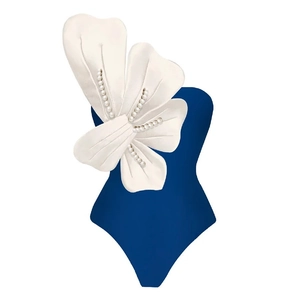 Detail of blue one-shoulder swimsuit with 3D white floral petals and pearl embellishments