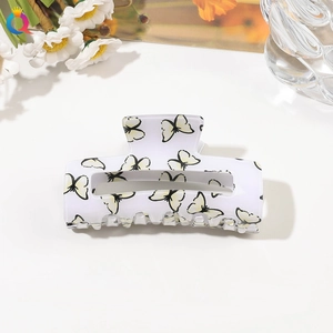 Detail shot of a white rectangular hair claw clip with yellow and black butterfly patterns