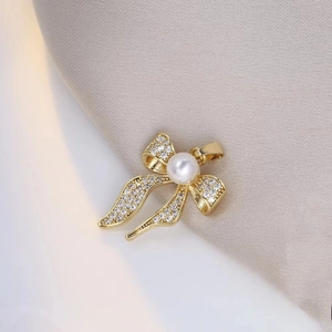 Detaillierte Nahaufnahme einer goldenen Schleife mit Zirkonia und einer weißen Perle