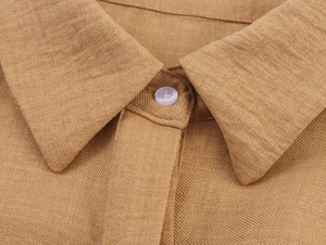Macro shot of brown twill shirt collar showing fine fabric texture and white button detail