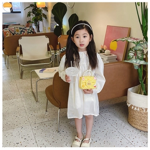 Little girl in white dress wearing yellow pearl handle crossbody bag in a cafe