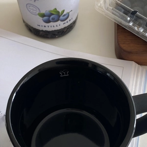 Close-up of black ceramic mug with 'drink more water' slogan and cute animal illustration
