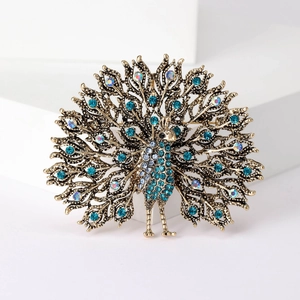 Macro detail of bronze peacock brooch featuring blue and iridescent rhinestones on white