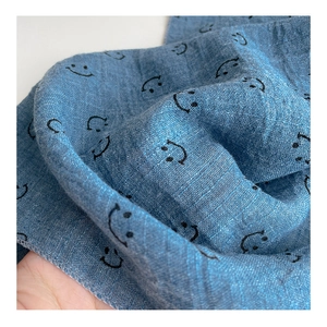 Close-up of blue breathable cotton gauze fabric featuring a minimalist black smiley face
