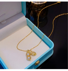 Vue détaillée d'un pendentif cacahuète doré avec perles et zircons dans un écrin bleu