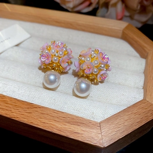Détail d'une boucle d'oreille florale sphérique avec des pétales roses et perle