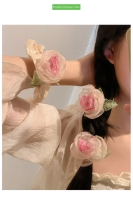Close-up of dried rose organza flower hair clip and wrist accessory in light peach pink