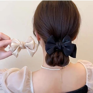 Detailed view of satin bow hair clips in black and champagne on an elegant bun