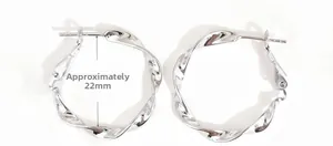 Dettaglio orecchini a cerchio ritorti argento 22mm con texture ondulata lucida
