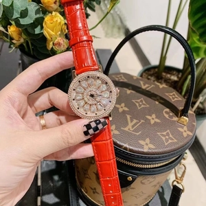 Detail of red leather luxury watch with gold diamond bezel held against designer bag