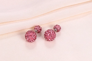 Macro shot of pink crystal double ball stud earrings on soft fabric background