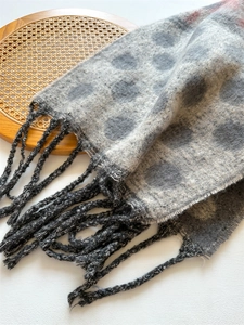 Detail of gray polka dot scarf featuring soft fabric texture and long woven tassels