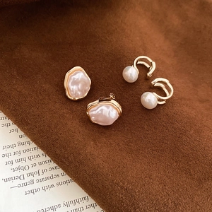 Detailed macro view of French vintage gold pearl ear cuffs on retro fabric background