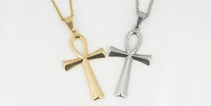 Detail view of gold and silver Ankh cross pendants on metal chains over white background