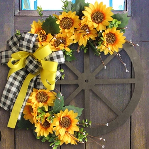 Sunflower wooden wheel wreath with black and white plaid bow hanging on a dark wood door