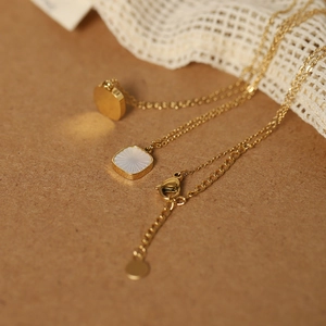 Detail view of African daisy shell engraving on a gold stainless steel necklace pendant