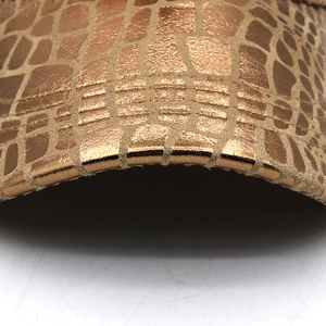 Macro detail of the metalized plaid pattern and fine stitching on the cap leather