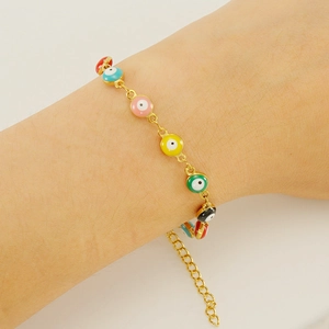 Detailed view of colorful evil eye beaded bracelets worn on a model's wrist with gold chain