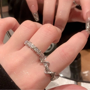 Close-up of interlocking silver rings with zircon stones on a reflective surface