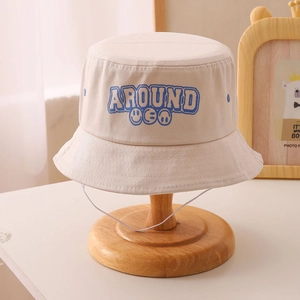 Detailed close-up of beige cotton fisherman hat with blue smiling face and windproof rope