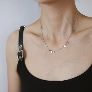 Close-up of minimalist silver piano square pendant necklace on a female model neck