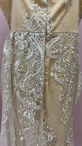 Détail d'une robe en dentelle champagne avec broderie florale blanche et sequins argentés