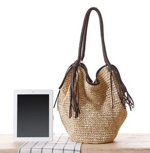 Sac bandoulière en paille avec anses marron foncé et longues franges sur tissu