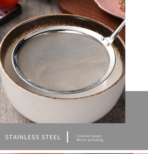 Close-up of a mirror-polished stainless steel fine mesh skimmer spoon on a ceramic bowl