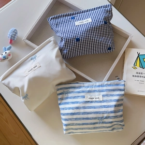 Detailed close-up of blue striped and plaid cotton makeup bags with delicate floral embroidery