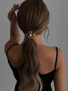 Detailed view of a gold flower hair tie with pearls on a brunette ponytail