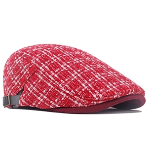 Dettaglio del cappello in tweed rosso a scacchi con cinturino in pelle grigia e fibbia