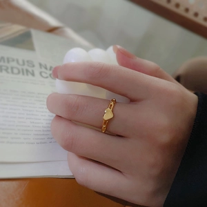 Bague cœur dorée minimaliste avec anneau en chaîne portée sur la main d'une femme