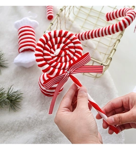 Close-up of plush red and white striped candy cane and lollipop ornaments with bows