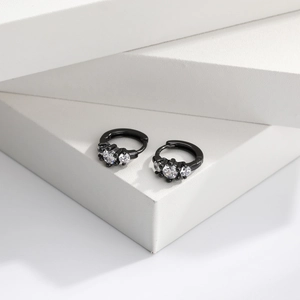 Detailed macro view of black plated sterling silver earrings with three clear zircons