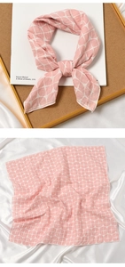 Detailed texture of pink cotton-linen scarf with geometric pattern tied on a book