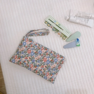 Pochette in cotone a fiori con chiusura a zip su uno sfondo trapuntato bianco puro