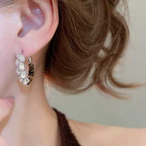 Close-up of 18k gold plated hoop earrings with zircon and tiger eye stone on ear