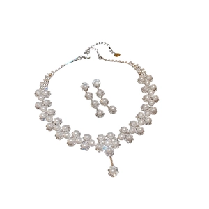 Elegant silver jewelry set with white pearls and sparkling rhinestones on white background