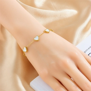 Gold plated stainless steel chain bracelet with white shell heart pendants on wrist