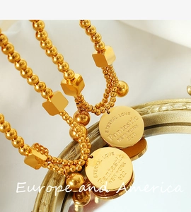 Close-up of 18k gold beads bracelet featuring engraved coin and square charms