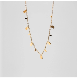Detail of minimalist gold chain necklace featuring multiple small rectangular metal pendants