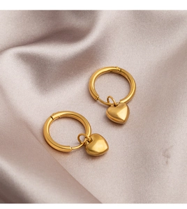 Detailed view of gold heart dangle earrings on a soft pink satin fabric background